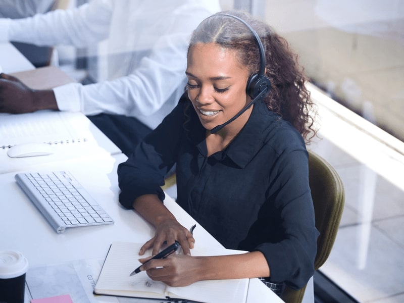 Smiling woman on call writing down important notes