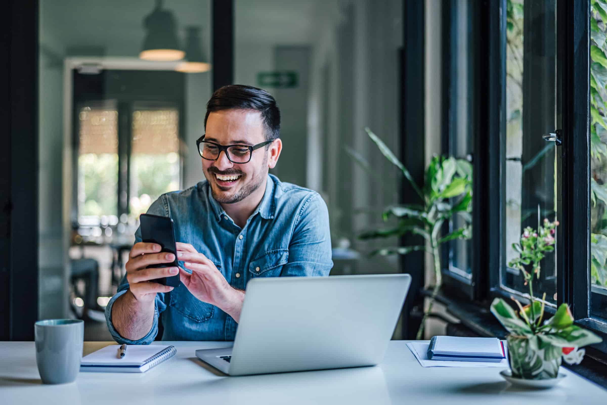 Happy adult man, writing a message to his colleague to take a break from work.